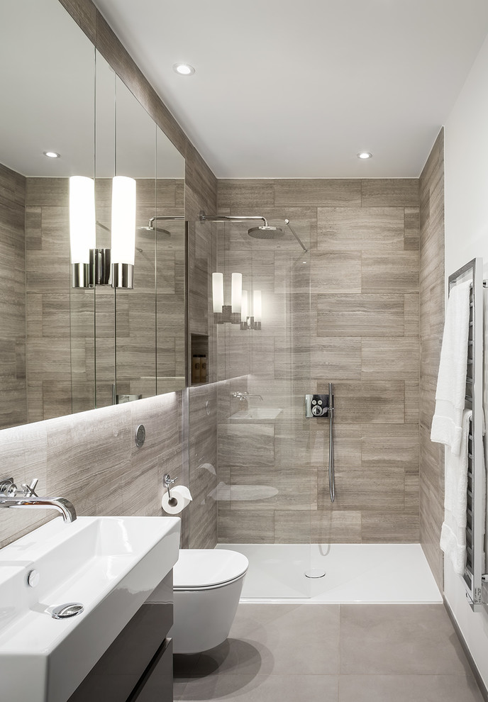 Small contemporary master bathroom in London with flat-panel cabinets, dark wood cabinets, an open shower, a one-piece toilet, beige tile, limestone, white walls, porcelain floors, a trough sink, grey floor and an open shower.