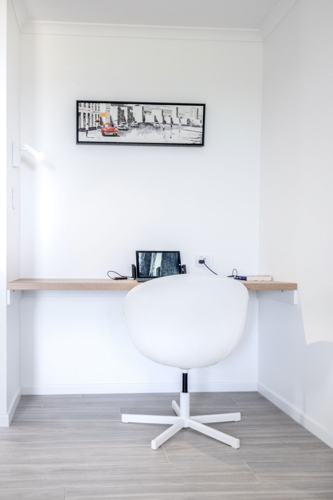 Diseño de despacho marinero pequeño con paredes blancas, suelo laminado, escritorio empotrado y suelo gris