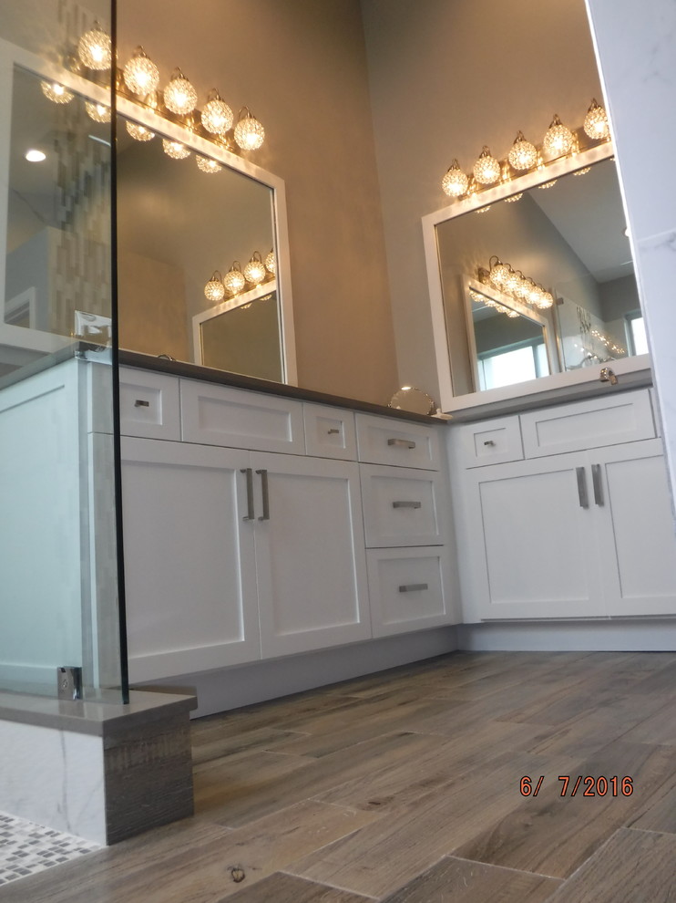 Large transitional master bathroom in Miami with shaker cabinets, white cabinets, an open shower, a two-piece toilet, gray tile, white tile, porcelain tile, grey walls, dark hardwood floors, an undermount sink, solid surface benchtops, brown floor and an open shower.