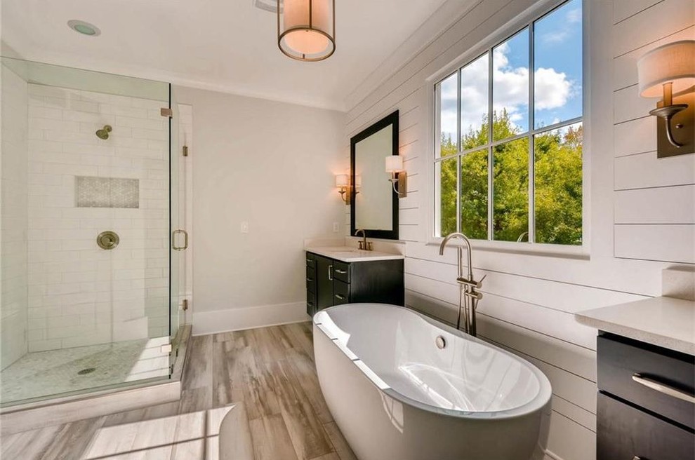 Design ideas for a mid-sized traditional master bathroom in Atlanta with raised-panel cabinets, black cabinets, a freestanding tub, a corner shower, white tile, subway tile, white walls, bamboo floors, an undermount sink, marble benchtops, beige floor, a hinged shower door and white benchtops.