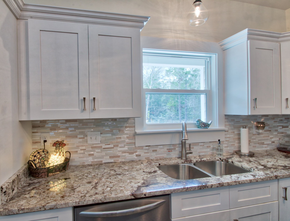 Mid-sized l-shaped eat-in kitchen photo with an undermount sink, shaker cabinets, yellow cabinets, granite countertops, glass tile backsplash, stainless steel appliances, an island and white countertops
