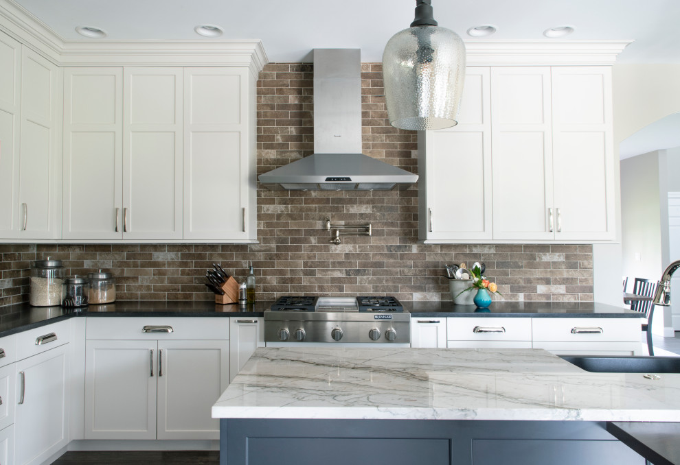 Kitchen - l-shaped gray floor kitchen idea with a farmhouse sink, white cabinets, quartz countertops, beige backsplash, ceramic backsplash, stainless steel appliances and an island