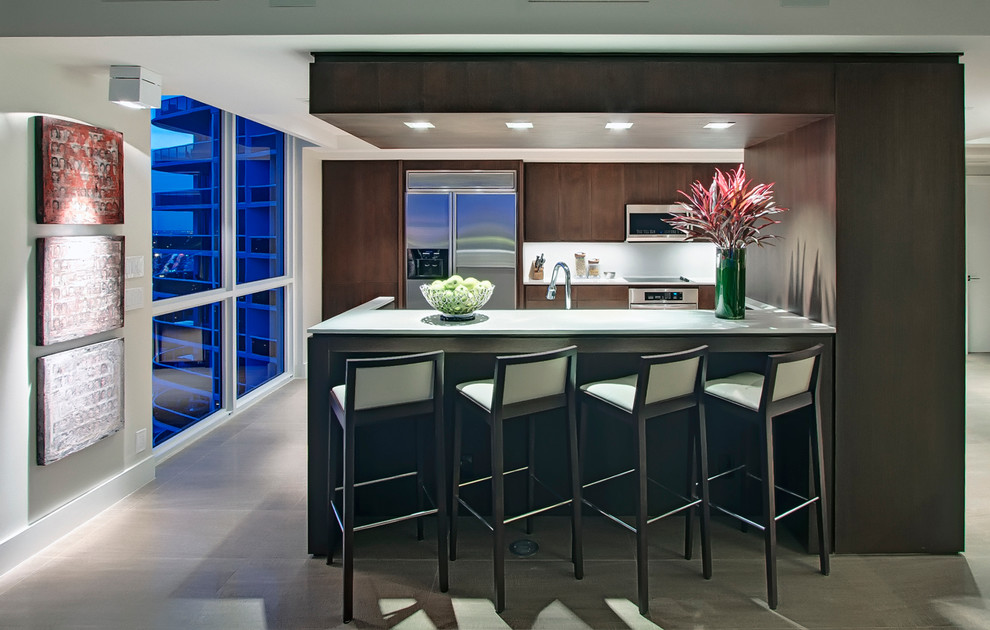 This is an example of a contemporary u-shaped kitchen in Miami with flat-panel cabinets, dark wood cabinets, quartzite benchtops, stainless steel appliances and a peninsula.