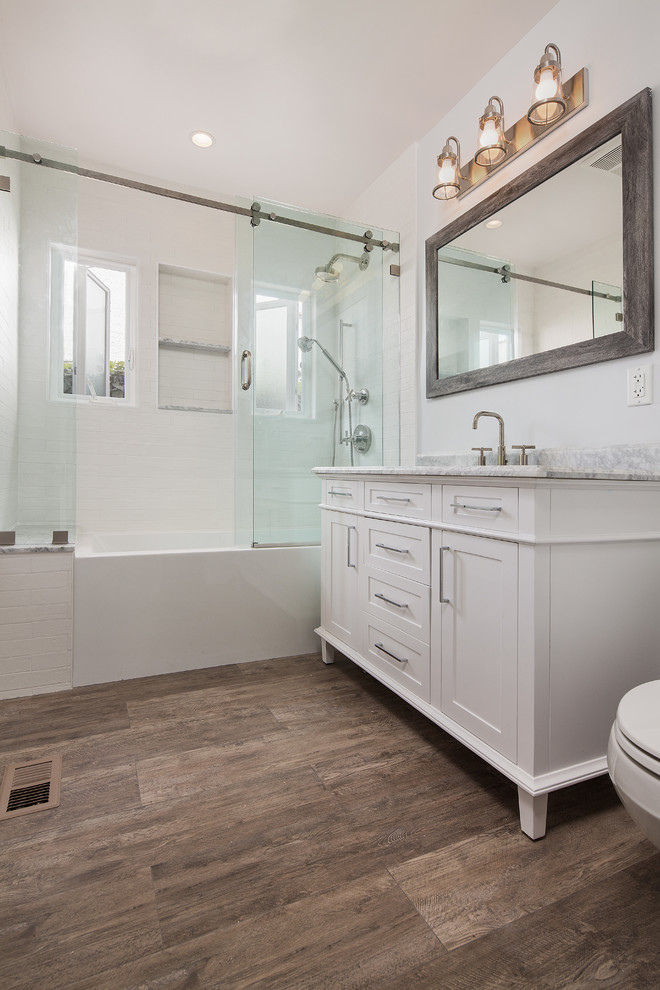 Design ideas for a small transitional kids bathroom in Los Angeles with furniture-like cabinets, white cabinets, an alcove tub, an alcove shower, a one-piece toilet, white tile, porcelain tile, grey walls, porcelain floors, an undermount sink, marble benchtops, brown floor, a sliding shower screen and grey benchtops.