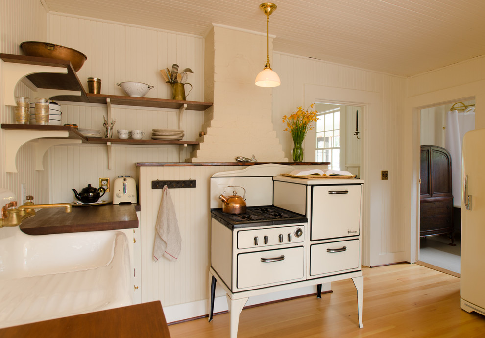 Photo of a beach style u-shaped eat-in kitchen in Portland with a farmhouse sink, open cabinets and wood benchtops.