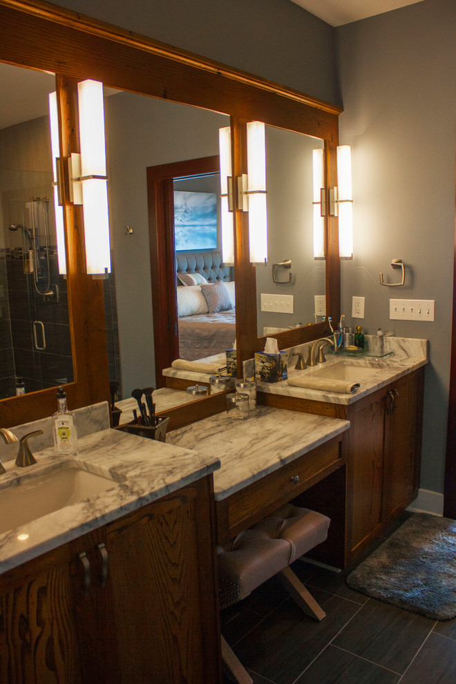 This is an example of an expansive contemporary master bathroom in Charlotte with shaker cabinets, dark wood cabinets, a corner tub, a corner shower, a two-piece toilet, multi-coloured tile, porcelain tile, porcelain floors, an undermount sink, granite benchtops, a hinged shower door, grey walls and grey floor.