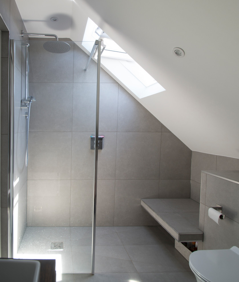 Photo of a small contemporary master bathroom in Surrey with flat-panel cabinets, brown cabinets, a curbless shower, a wall-mount toilet, gray tile, cement tile, grey walls, ceramic floors, a drop-in sink, laminate benchtops, grey floor and an open shower.