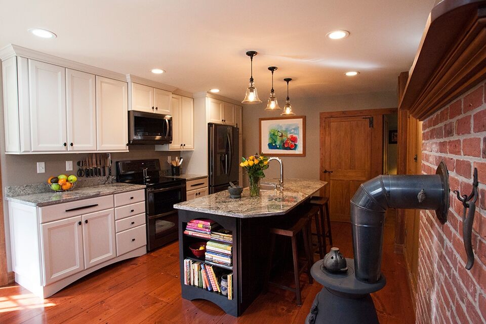 This is an example of a small transitional eat-in kitchen in Providence with a farmhouse sink, flat-panel cabinets, grey cabinets, granite benchtops, grey splashback, black appliances, medium hardwood floors and with island.