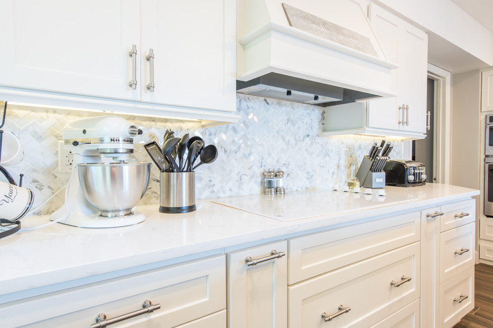 Inspiration for a large transitional u-shaped porcelain tile and brown floor eat-in kitchen remodel with an undermount sink, shaker cabinets, white cabinets, quartz countertops, white backsplash, marble backsplash, stainless steel appliances and two islands