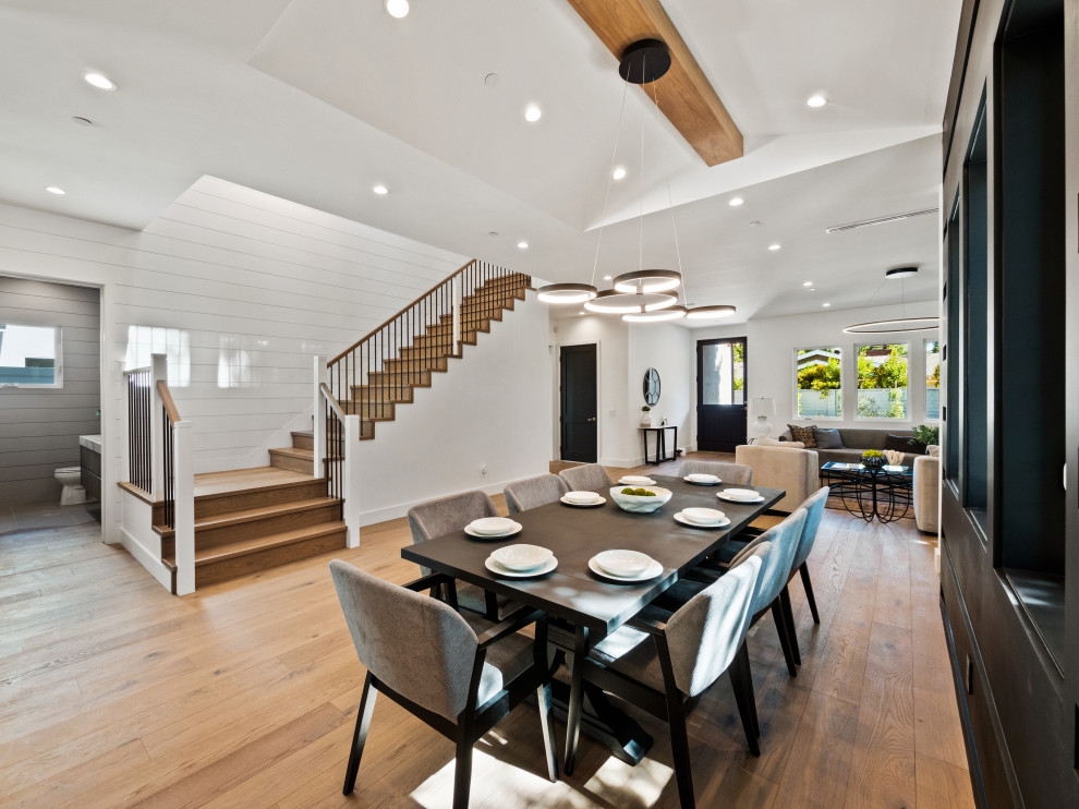 This is an example of a large country open plan dining in Los Angeles with black walls, medium hardwood floors, exposed beam and panelled walls.