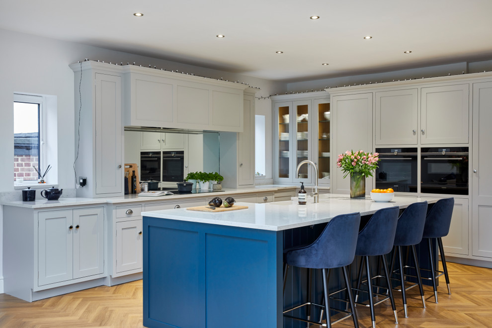 Large contemporary u-shaped open plan kitchen in Kent with a double-bowl sink, with island and white benchtop.