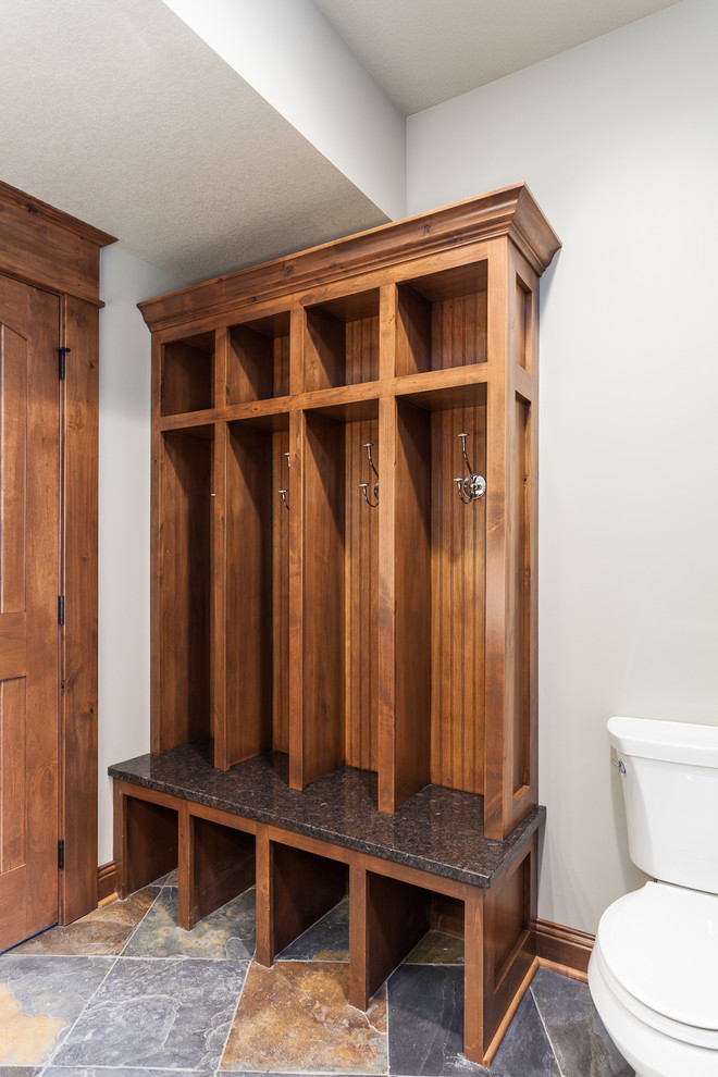 Large mountain style multicolored tile and stone tile slate floor doorless shower photo with a console sink, flat-panel cabinets, medium tone wood cabinets, granite countertops, a two-piece toilet and beige walls