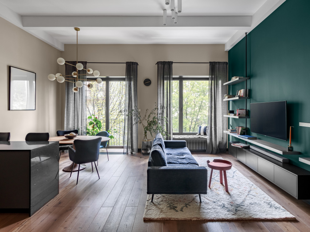 Стильный дизайн: гостиная комната в современном стиле с с книжными шкафами и полками, зелеными стенами и телевизором на стене - последний тренд