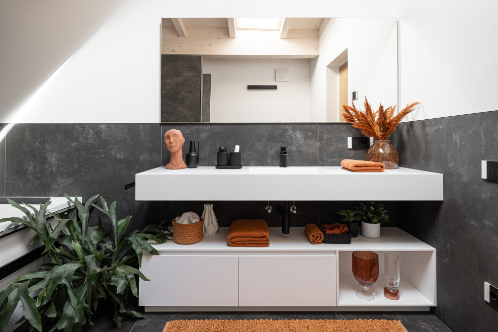 Design ideas for a contemporary bathroom in Other with flat-panel cabinets, white cabinets, black tile, porcelain tile, black walls, ceramic floors, an integrated sink, solid surface benchtops, black floor, white benchtops, a built-in vanity and exposed beam.