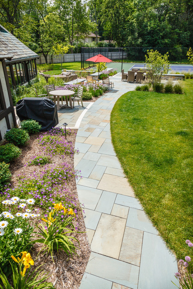 Photo of a large traditional backyard patio in Milwaukee with natural stone pavers.