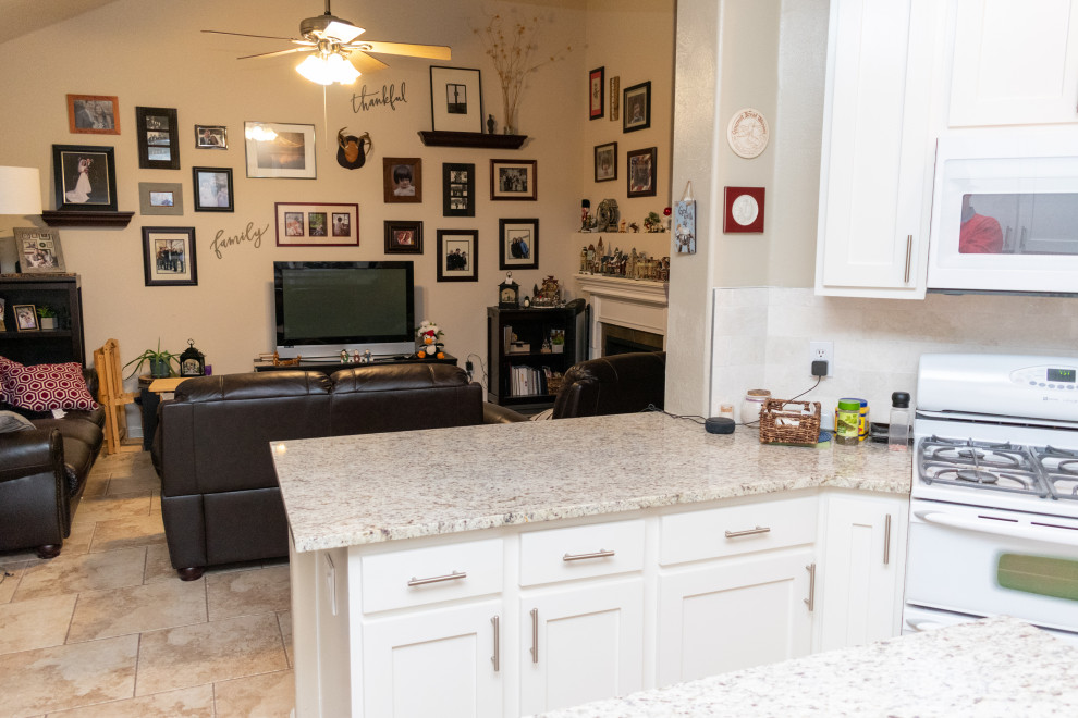Foto på ett mellanstort vintage beige kök, med en nedsänkt diskho, skåp i shakerstil, vita skåp, granitbänkskiva, beige stänkskydd, stänkskydd i stenkakel, vita vitvaror, cementgolv, en köksö och beiget golv