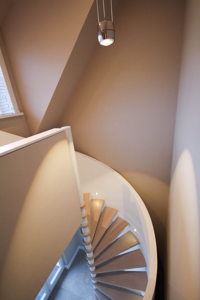 Aménagement d'un très grand escalier courbe contemporain avec des marches en bois peint.