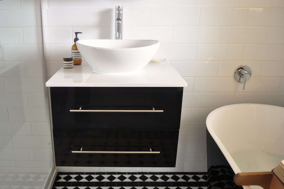 Mid-sized traditional master bathroom in Melbourne with black cabinets, a freestanding tub, black and white tile, porcelain tile, white walls, porcelain floors, a vessel sink and quartzite benchtops.