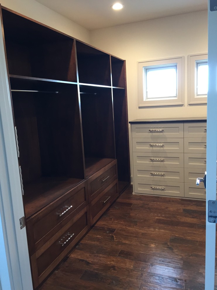 Photo of a mid-sized transitional gender-neutral walk-in wardrobe in Omaha with shaker cabinets, brown cabinets, dark hardwood floors and brown floor.