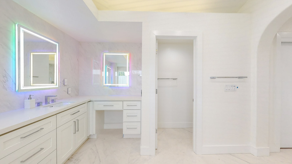 Bild på ett vit vitt badrum, med vita skåp, ett fristående badkar, en hörndusch, flerfärgad kakel, marmorkakel, flerfärgade väggar, marmorgolv, ett undermonterad handfat, bänkskiva i kvartsit, flerfärgat golv och dusch med gångjärnsdörr