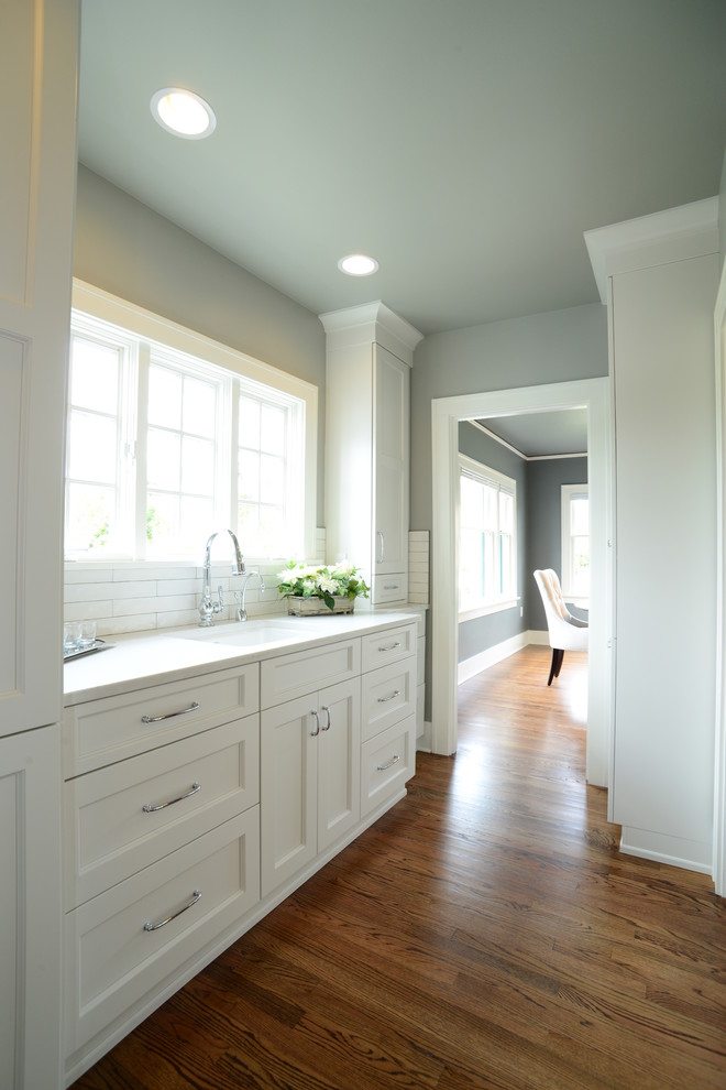 Eat-in kitchen - large transitional l-shaped medium tone wood floor eat-in kitchen idea in Seattle with an undermount sink, shaker cabinets, quartz countertops, white backsplash, subway tile backsplash, paneled appliances and an island
