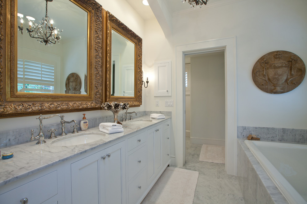 Photo of a traditional bathroom in Tampa with an undermount sink, recessed-panel cabinets, white cabinets, a drop-in tub and gray tile.