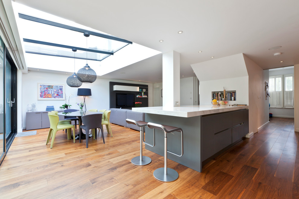 This is an example of a mid-sized contemporary kitchen/dining combo in London with white walls and medium hardwood floors.