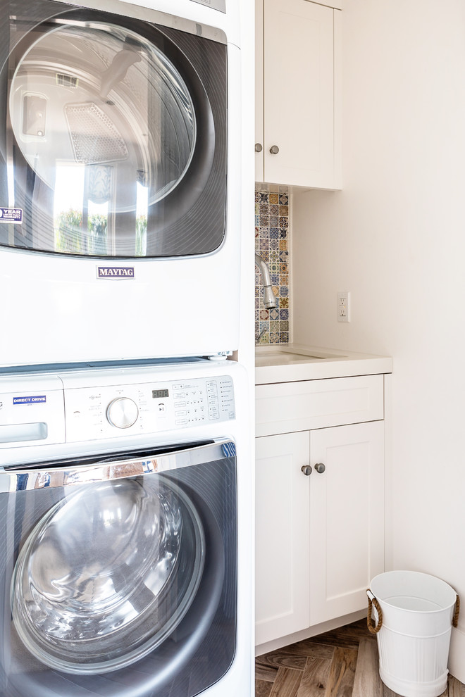 Mid-sized beach style single-wall dedicated laundry room in Sacramento with an undermount sink, shaker cabinets, white cabinets, quartz benchtops, medium hardwood floors, an integrated washer and dryer, white benchtop and white walls.