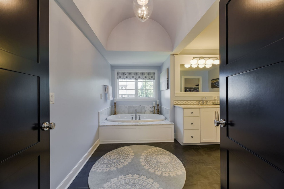 Inspiration for a mid-sized transitional master gray tile and marble tile double-sink, porcelain tile, beige floor and vaulted ceiling drop-in bathtub remodel in Chicago with white cabinets, a freestanding vanity, recessed-panel cabinets, white walls, marble countertops and white countertops