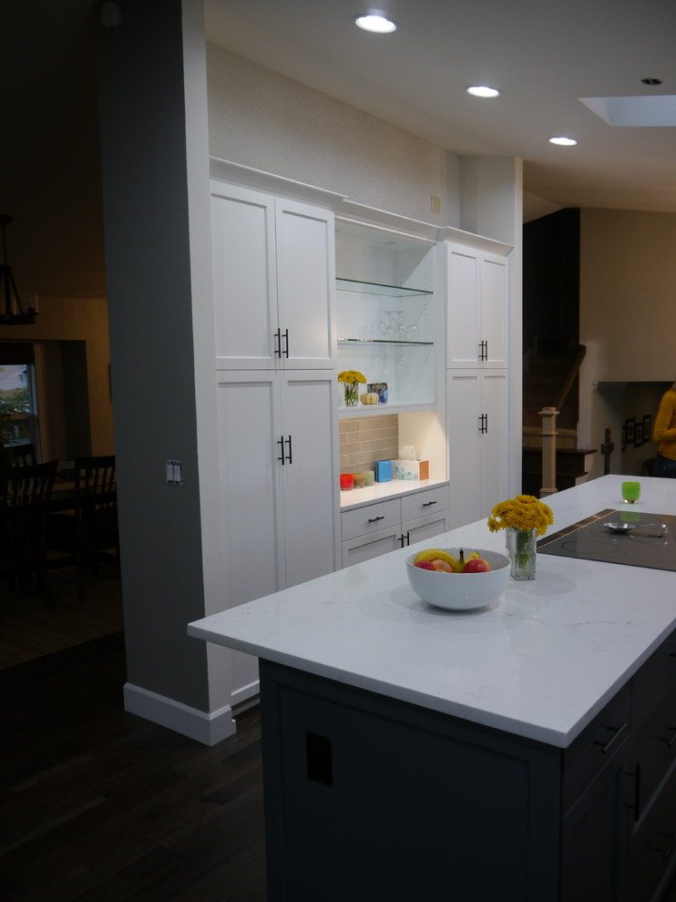 Inspiration for a large transitional dark wood floor and brown floor eat-in kitchen remodel in Seattle with a single-bowl sink, shaker cabinets, white cabinets, solid surface countertops, beige backsplash, ceramic backsplash, stainless steel appliances, an island and white countertops