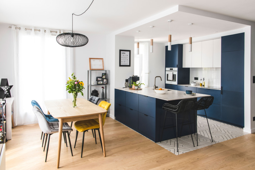 Medium sized contemporary galley open plan kitchen in Lyon with a submerged sink, flat-panel cabinets, blue cabinets, laminate countertops, white splashback, ceramic splashback, integrated appliances, ceramic flooring, an island, white floors, white worktops and a coffered ceiling.