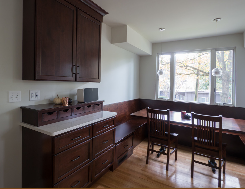 Example of a mid-sized transitional u-shaped medium tone wood floor and brown floor eat-in kitchen design in Cedar Rapids with recessed-panel cabinets, dark wood cabinets, quartz countertops and stainless steel appliances