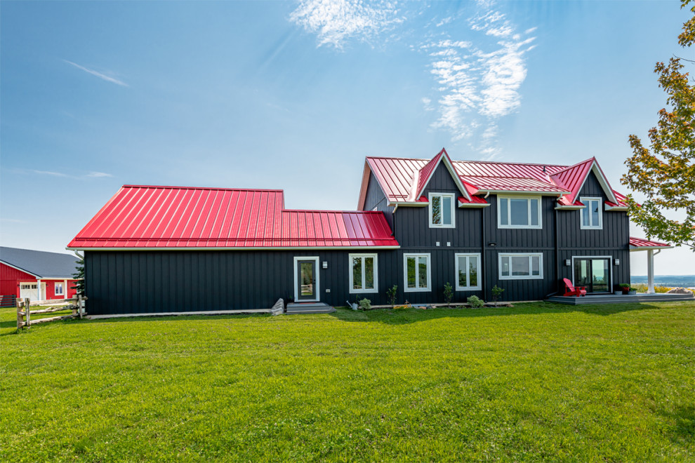 Immagine della villa nera country a due piani con rivestimento in vinile, tetto rosso e pannelli e listelle di legno