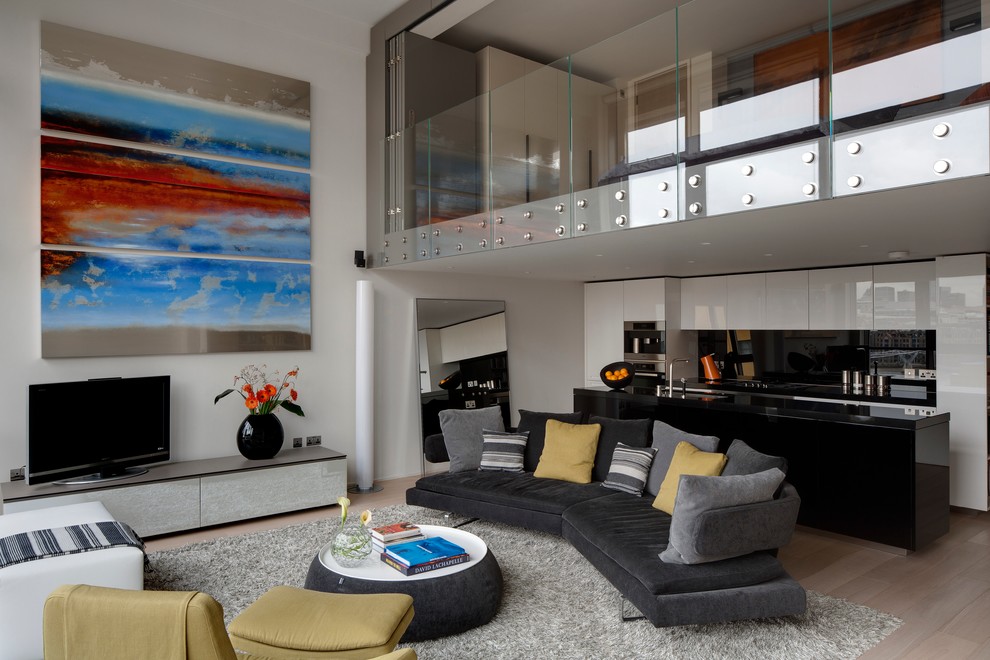 This is an example of a contemporary formal open concept living room in London with grey walls, light hardwood floors, no fireplace and a freestanding tv.