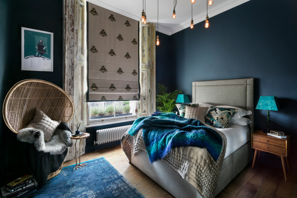 Design ideas for an eclectic master bedroom in London with blue walls, no fireplace and medium hardwood floors.