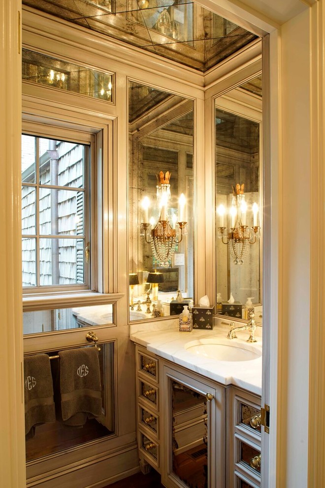 Inspiration for a mid-sized traditional powder room in Other with a two-piece toilet, white tile, beaded inset cabinets, dark hardwood floors, an undermount sink and marble benchtops.