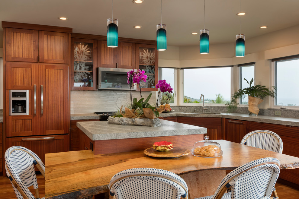 Inspiration for a large tropical u-shaped eat-in kitchen in Hawaii with a drop-in sink, flat-panel cabinets, dark wood cabinets, granite benchtops, white splashback, glass tile splashback, stainless steel appliances, dark hardwood floors, with island and brown floor.