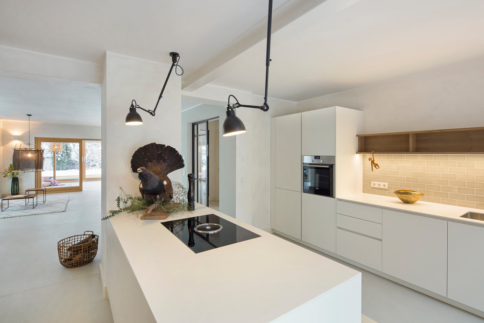 Inspiration for a mid-sized scandinavian galley open plan kitchen in Berlin with white cabinets, with island, an integrated sink, flat-panel cabinets, beige splashback, subway tile splashback, black appliances, white floor and white benchtop.