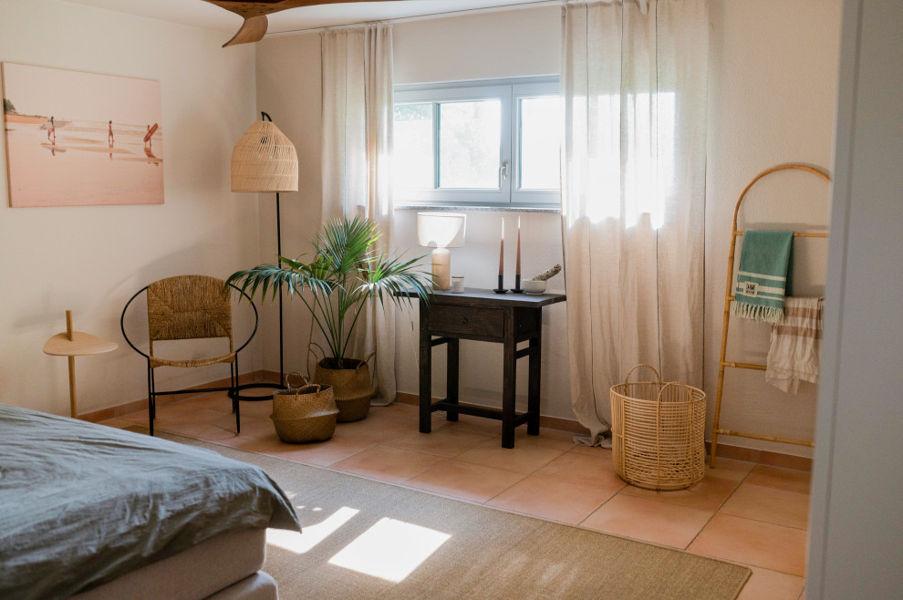 Modelo de dormitorio principal mediterráneo de tamaño medio con paredes beige, suelo de baldosas de terracota, estufa de leña y suelo naranja