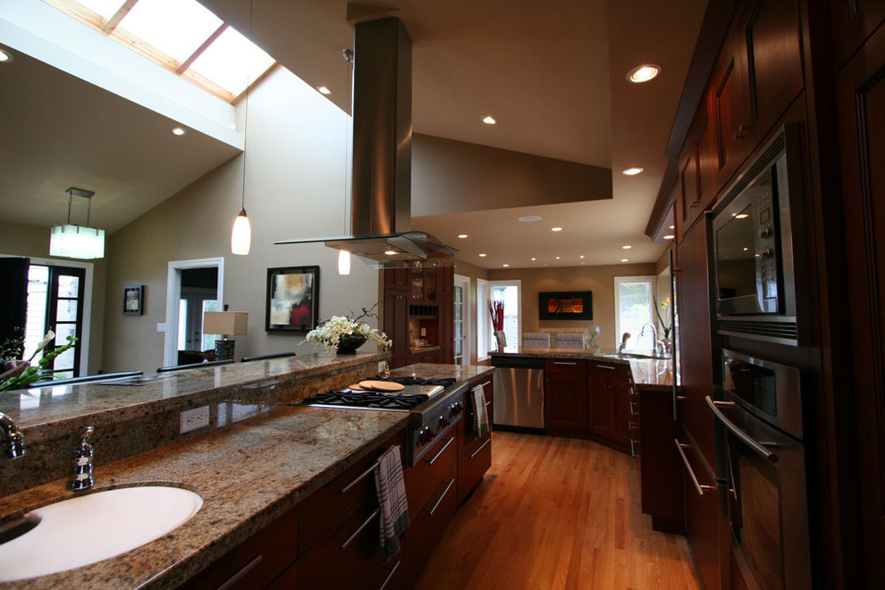 Photo of a traditional l-shaped open plan kitchen in Vancouver with stainless steel appliances, an undermount sink, recessed-panel cabinets, dark wood cabinets and granite benchtops.