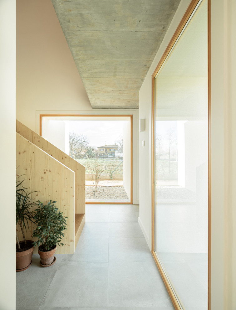 他の地域にある高級な広い地中海スタイルのおしゃれな玄関ロビー (白い壁、セラミックタイルの床、淡色木目調のドア、グレーの床、格子天井) の写真