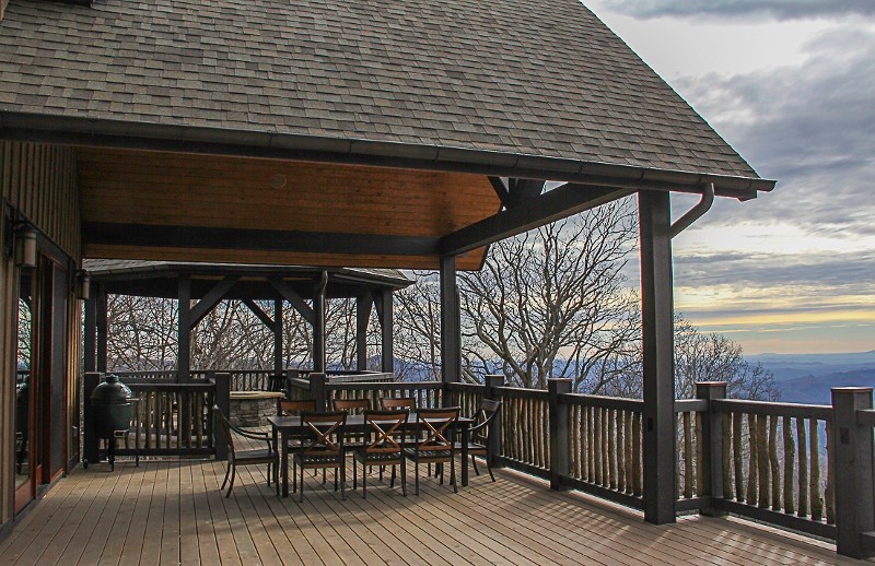 Deck - huge rustic backyard deck idea in Charlotte with a fire pit and a roof extension