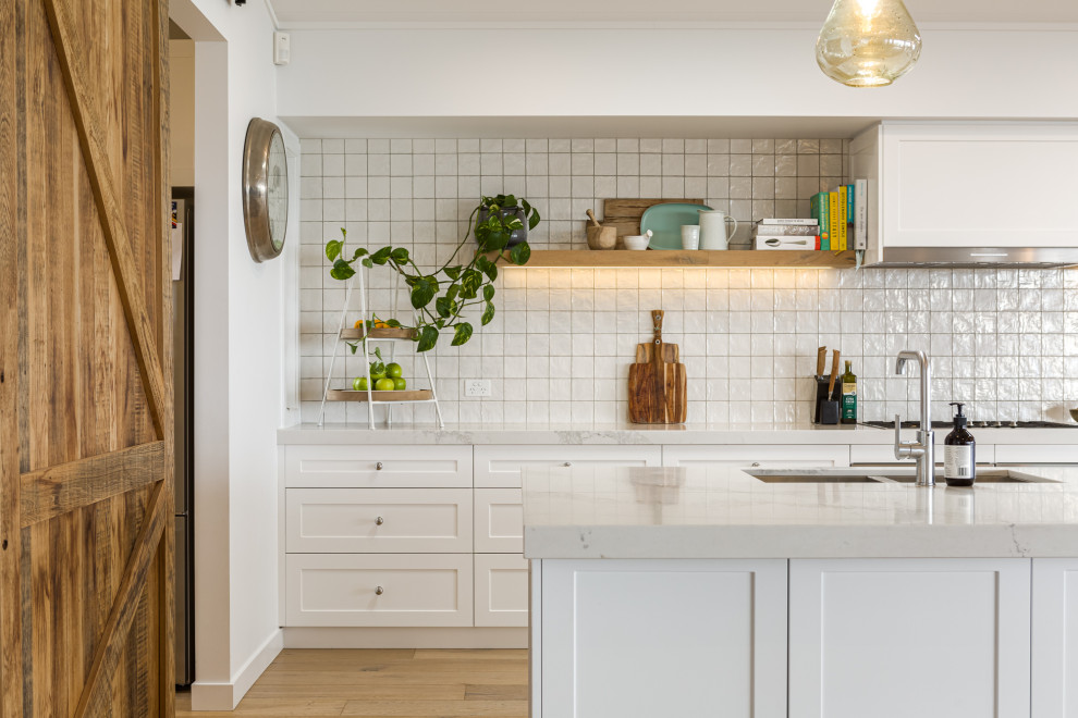 Photo of a mid-sized transitional galley kitchen in Melbourne with a double-bowl sink, shaker cabinets, white cabinets, medium hardwood floors, with island, beige floor and grey benchtop.