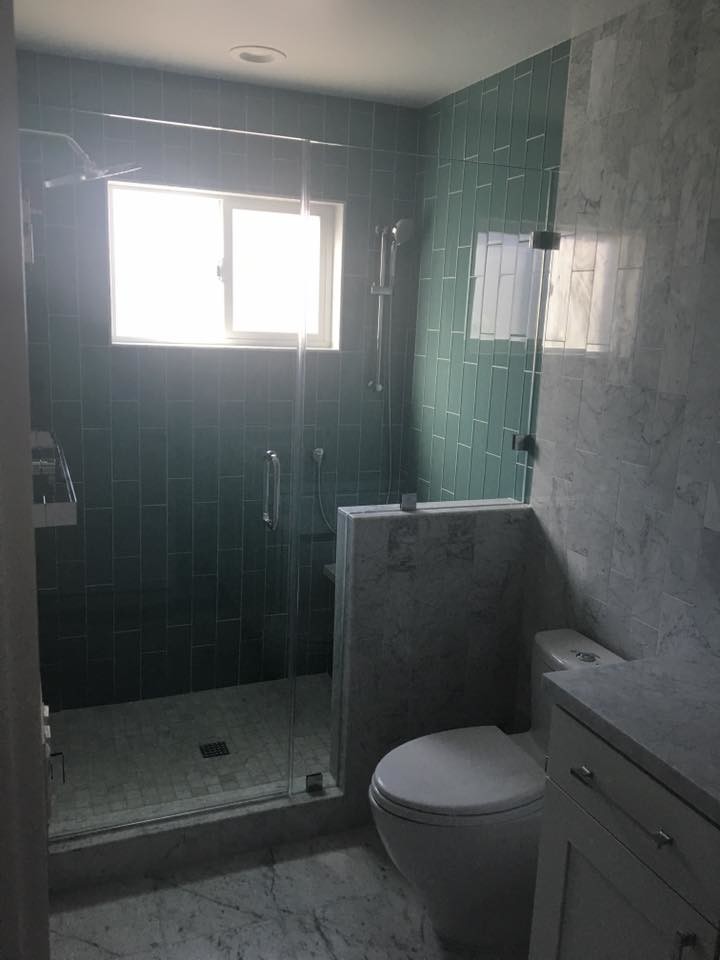 This is an example of a mid-sized contemporary bathroom in San Francisco with shaker cabinets, white cabinets, an alcove shower, a two-piece toilet, blue tile, glass tile, grey walls, marble floors, marble benchtops, grey floor and a hinged shower door.
