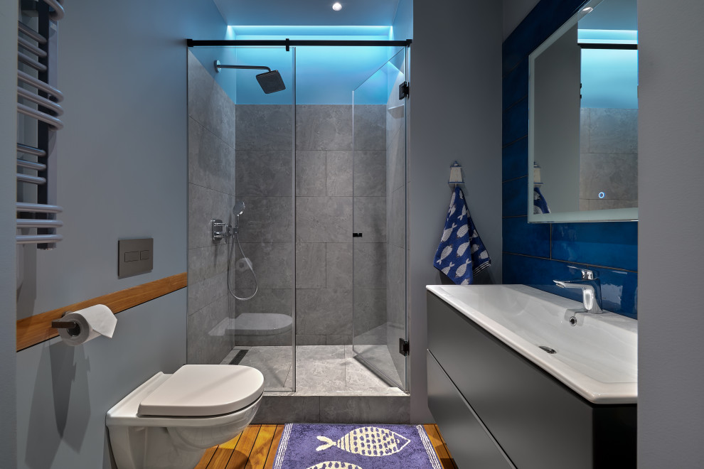 Свежая идея для дизайна: маленькая ванная комната в современном стиле с плоскими фасадами, серыми фасадами, душевой комнатой, инсталляцией, синей плиткой, керамогранитной плиткой, серыми стенами, полом из керамогранита, душевой кабиной, монолитной раковиной, серым полом, душем с распашными дверями, нишей, тумбой под одну раковину, подвесной тумбой и многоуровневым потолком для на участке и в саду - отличное фото интерьера