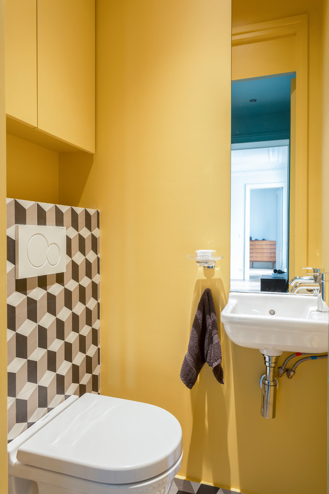 Inspiration for a contemporary powder room in Paris with a wall-mount toilet, multi-coloured tile, yellow walls and a wall-mount sink.