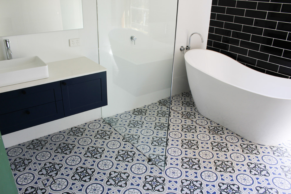 Inspiration for a large master wet room bathroom in Perth with shaker cabinets, blue cabinets, a freestanding tub, a one-piece toilet, white tile, ceramic tile, white walls, mosaic tile floors, a vessel sink, engineered quartz benchtops, multi-coloured floor, an open shower and white benchtops.