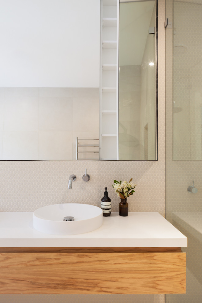 Photo of a mid-sized contemporary kids bathroom in Sydney with furniture-like cabinets, medium wood cabinets, a wall-mount toilet, beige tile, mosaic tile, beige walls, porcelain floors, a pedestal sink, wood benchtops and beige floor.