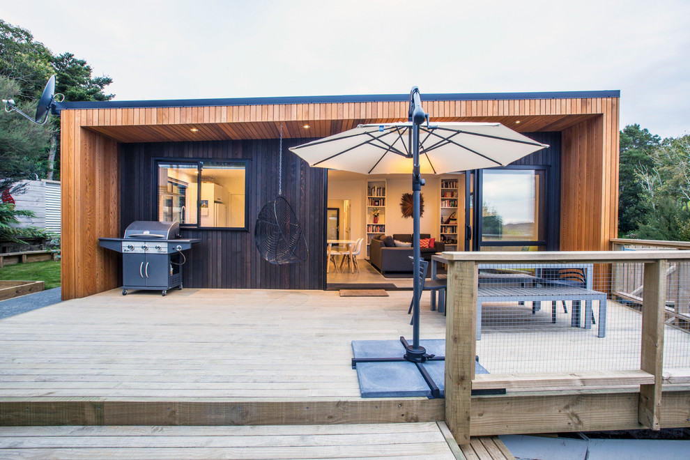 Mid-sized contemporary backyard deck in Auckland with an awning.