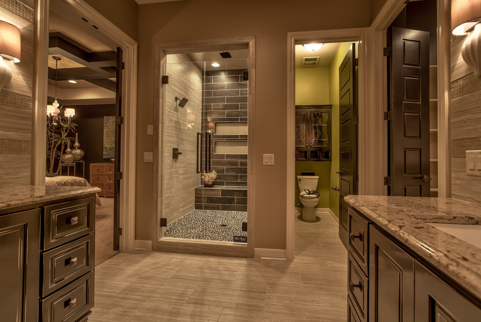 Large country master bathroom in Omaha with raised-panel cabinets, dark wood cabinets, a freestanding tub, an alcove shower, brown tile, porcelain tile, brown walls, porcelain floors, an undermount sink, granite benchtops, beige floor and a hinged shower door.